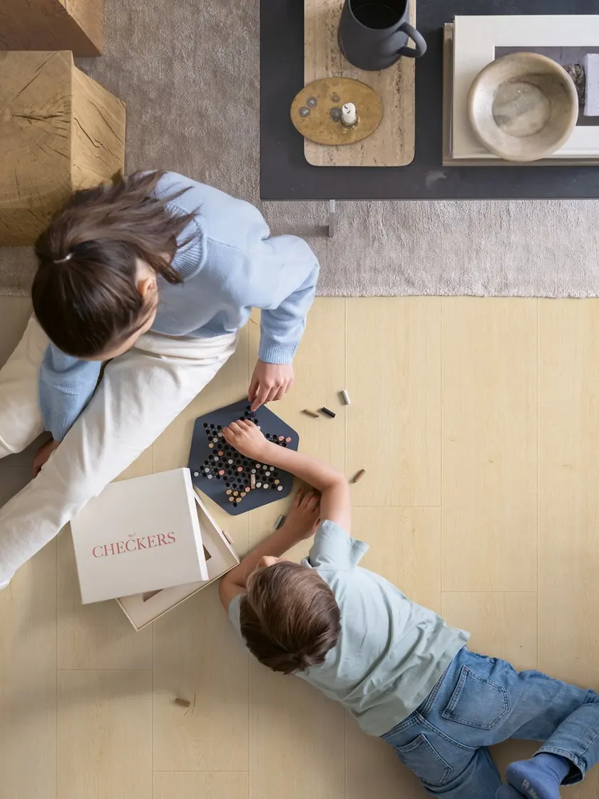 A parent and child playing a board game on a Pergo floor